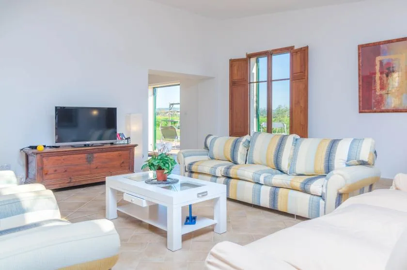 A bright living room with striped seating, a coffee table, and a television.