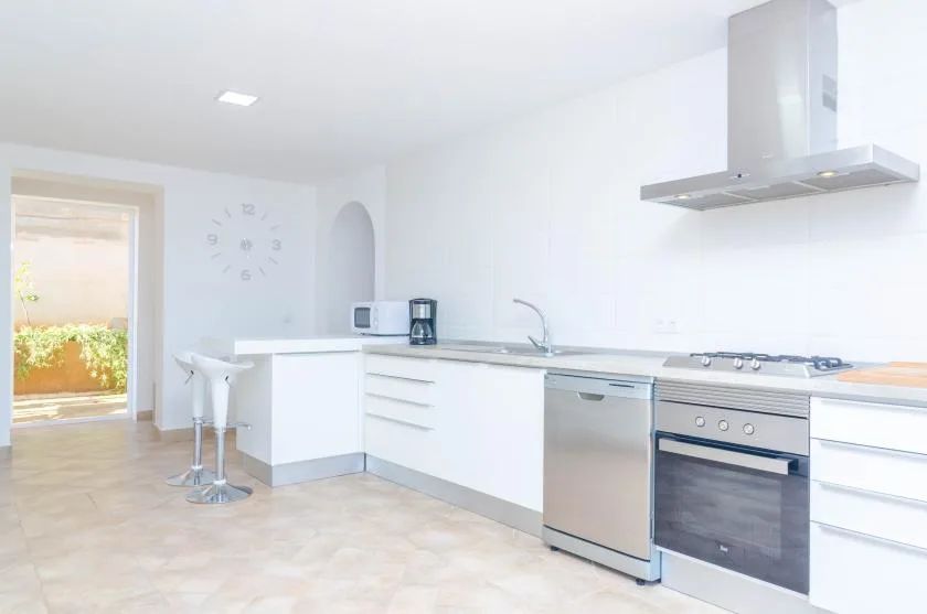 A bright kitchen with white cabinetry, a sink, and cooking appliances.