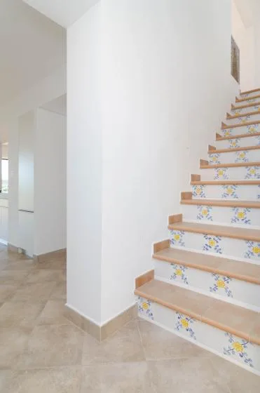 An indoor staircase has patterned risers and wooden-colored tread edges.
