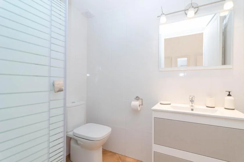 A bright bathroom with a shower, toilet, and vanity.