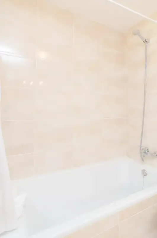 A bathroom with a bathtub and wall-mounted showerhead.