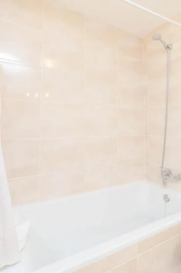 A bathroom with a bathtub and tiled walls.