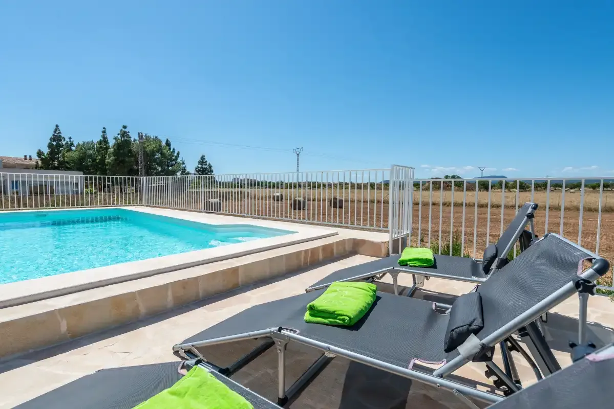 An outdoor swimming pool beside reclining loungers on a sunny terrace.