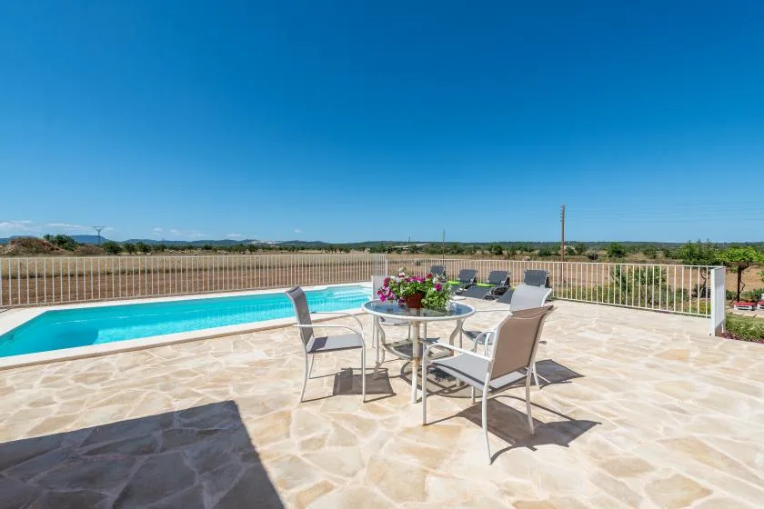A sunlit outdoor patio with a swimming pool and dining table.