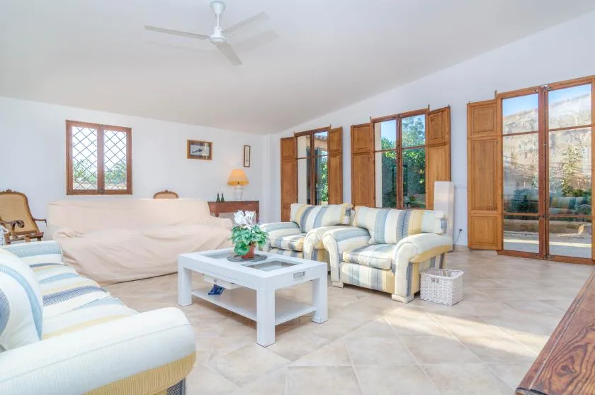 A bright living room with seating around a white coffee table and large windows.