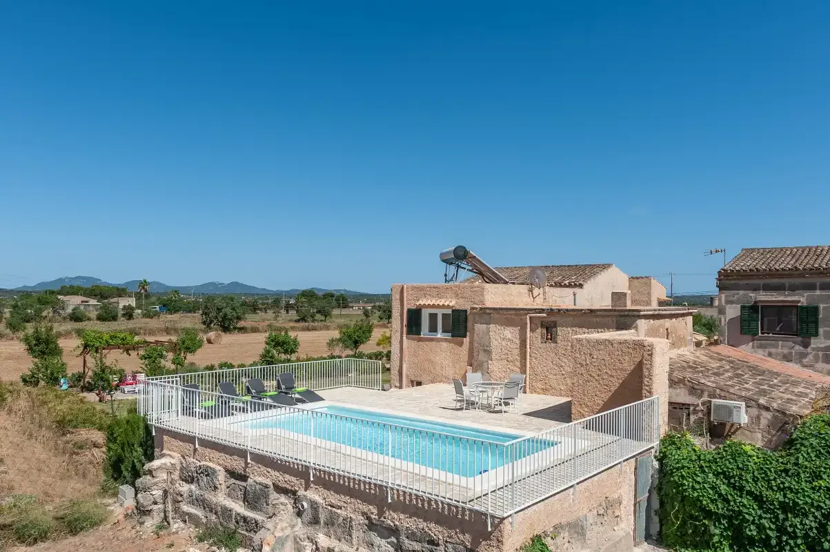 A swimming pool beside a stone building, with open countryside in the background.