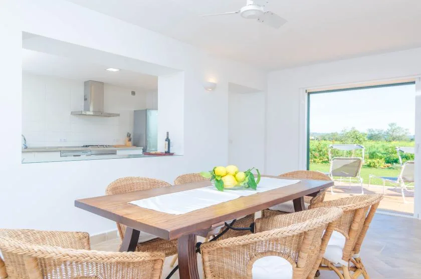 A dining area with a wooden table and wicker seating beside an open patio door.