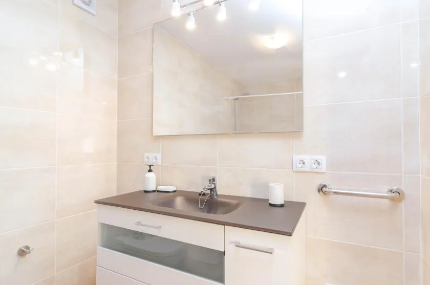 A bathroom vanity with a wide mirror and wall-mounted towel bar.