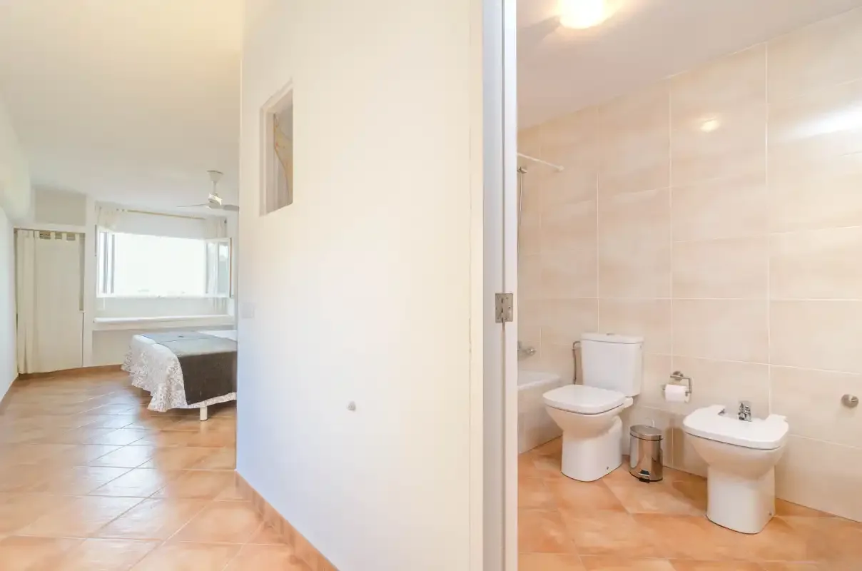 A bedroom with an adjacent bathroom featuring a toilet and sink.