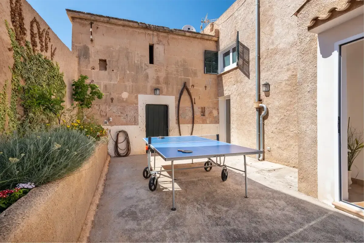 A stone courtyard with a table tennis table and a planted garden bed.