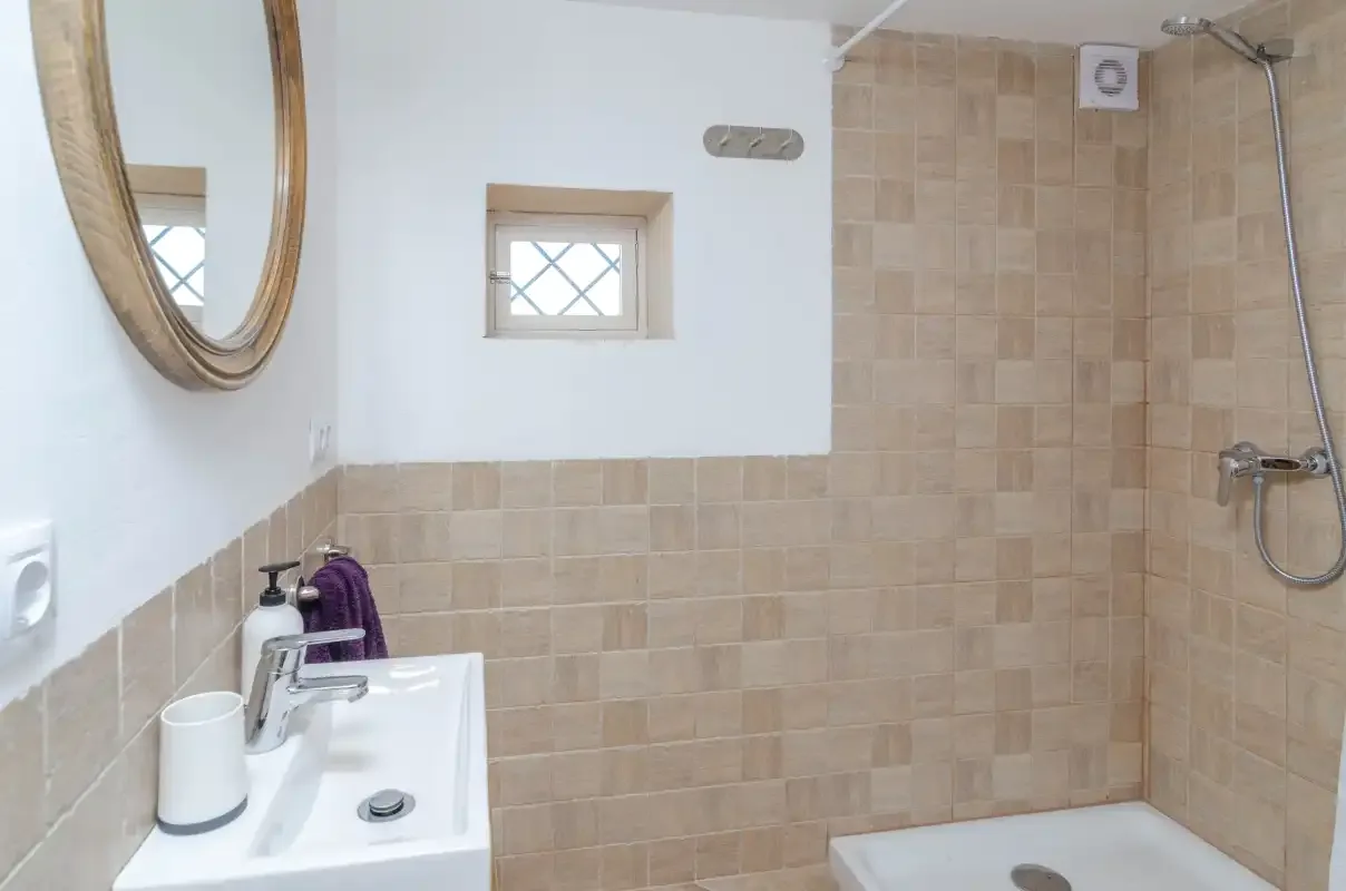A tiled bathroom with a sink, mirror, and shower.