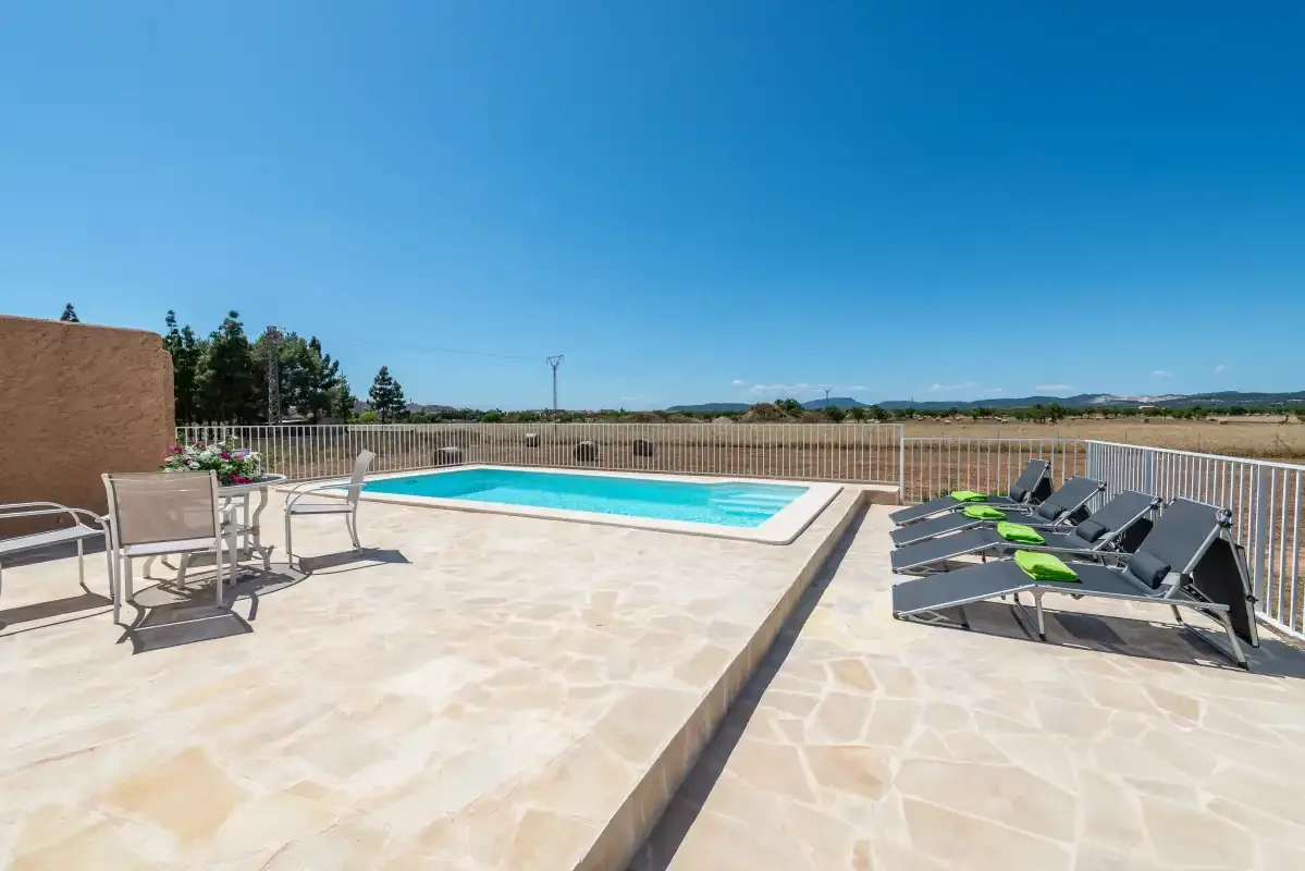 An outdoor swimming pool beside a tiled patio with loungers.