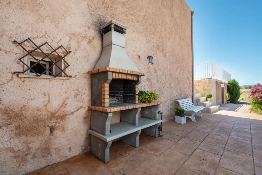 An outdoor patio features a built-in barbecue and a small seating area.