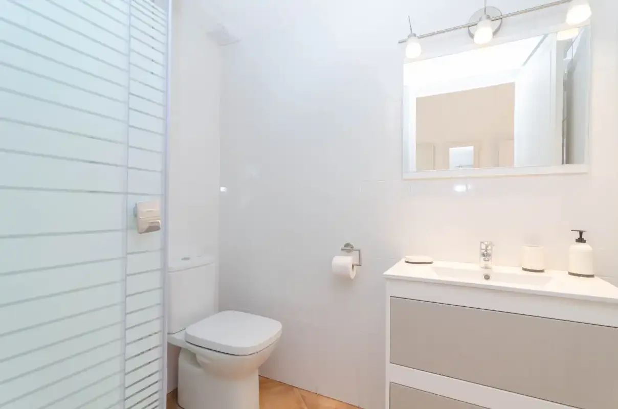 A bright bathroom with a sink, mirror, and shower.