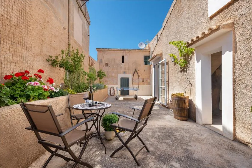 A sunny stone courtyard with outdoor seating and potted plants.