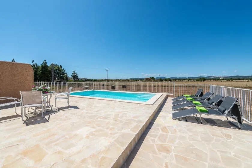 An outdoor pool and paved patio with lounge seating beside it.