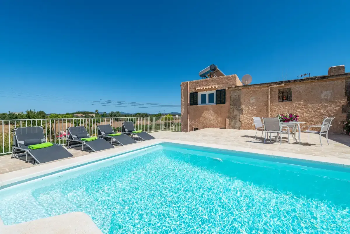 A rooftop swimming pool beside a terrace with lounge seating and a table.