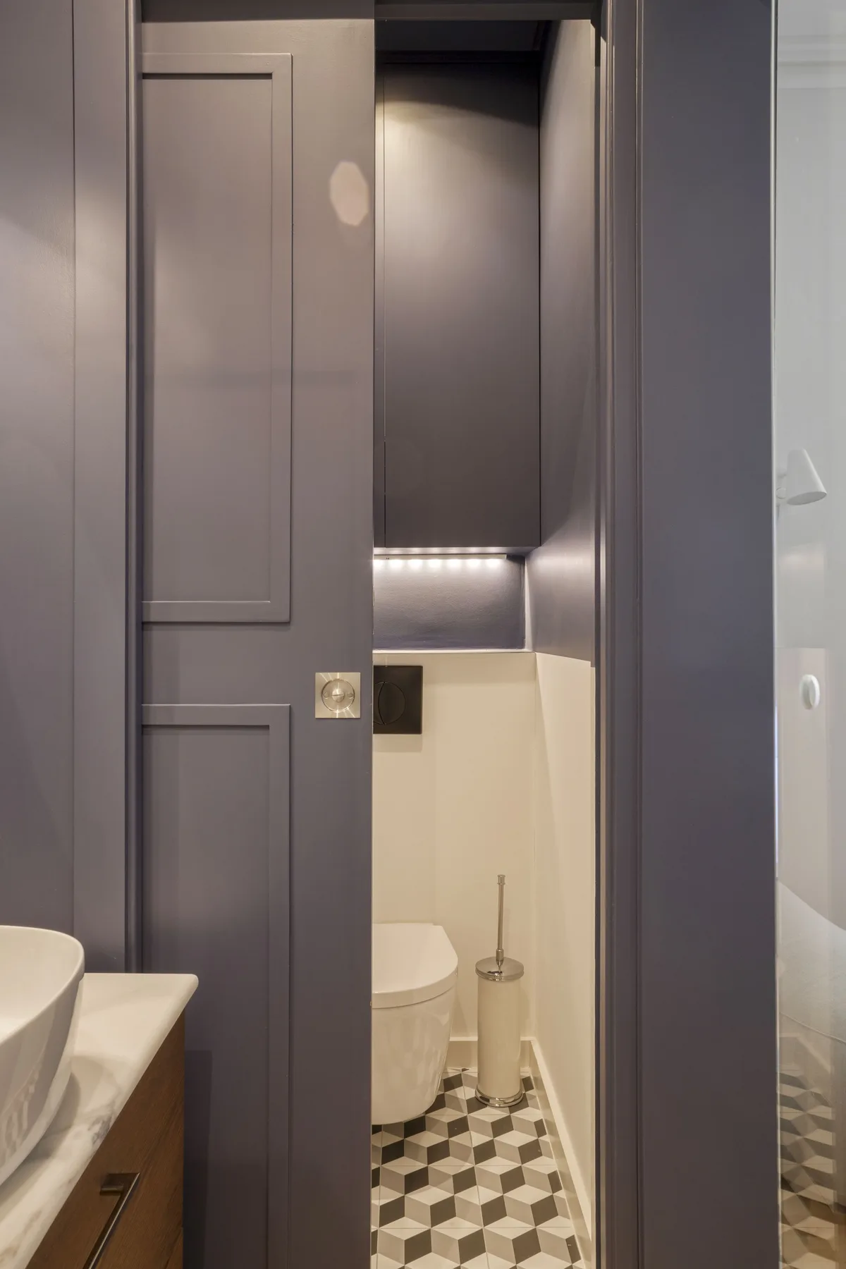 Un baño compacto con inodoro, lavabo y suelo de baldosas estampadas.