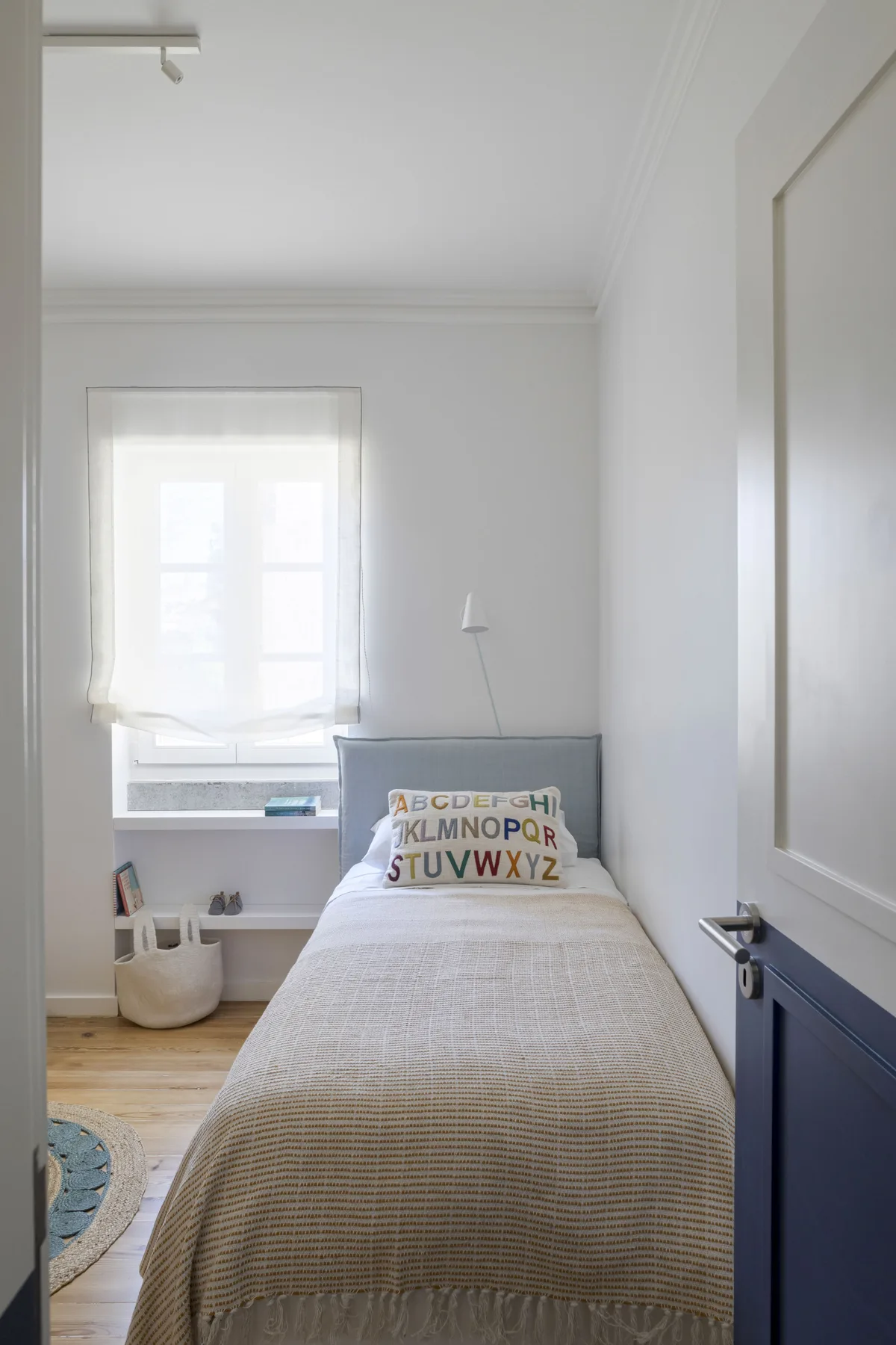 Un dormitorio luminoso con una cama individual y una ventana grande.