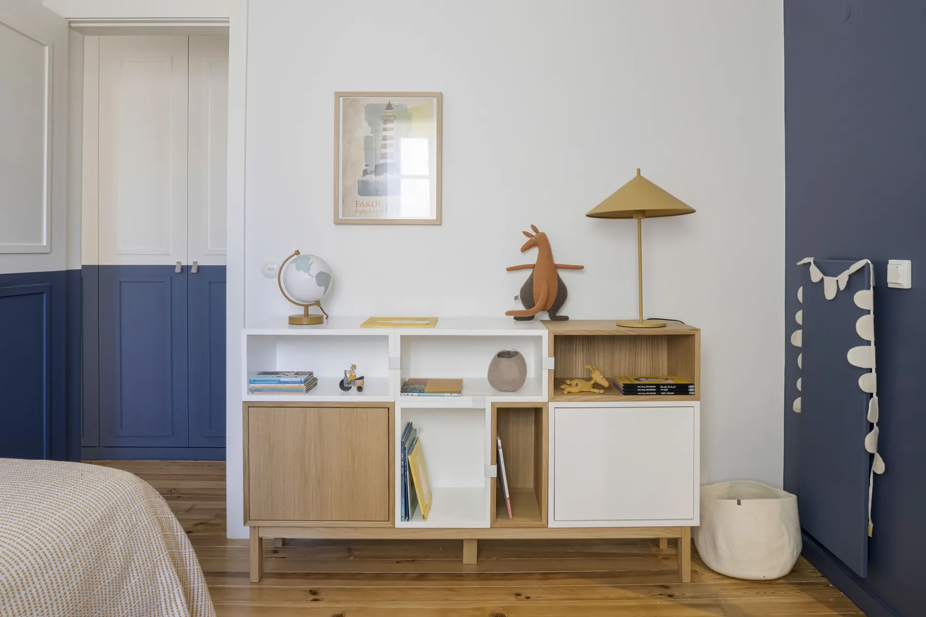 Un dormitorio con un mueble bajo de almacenamiento y una lámina enmarcada en la pared.