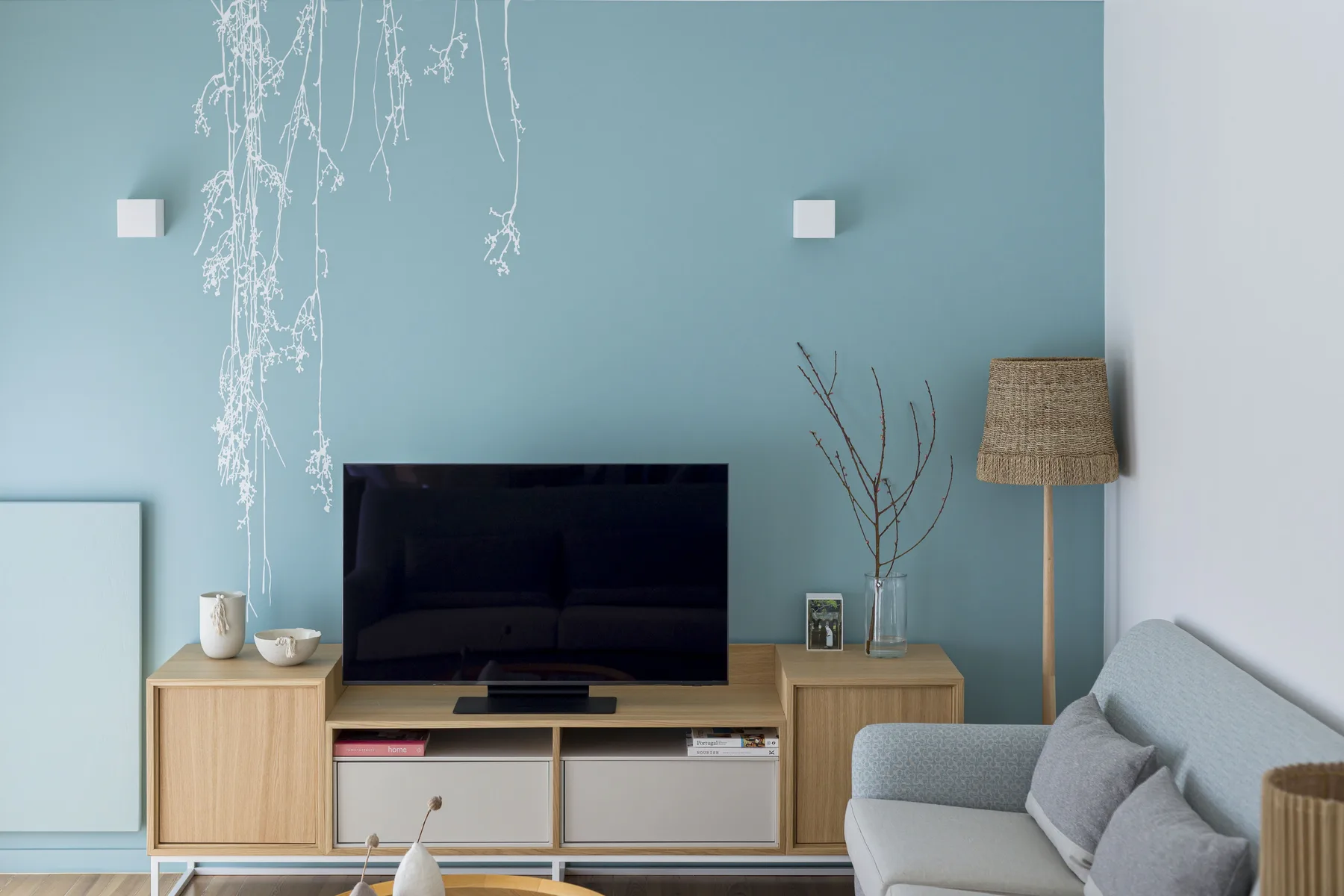 Una sala de estar con televisión, muebles de madera clara y asientos.