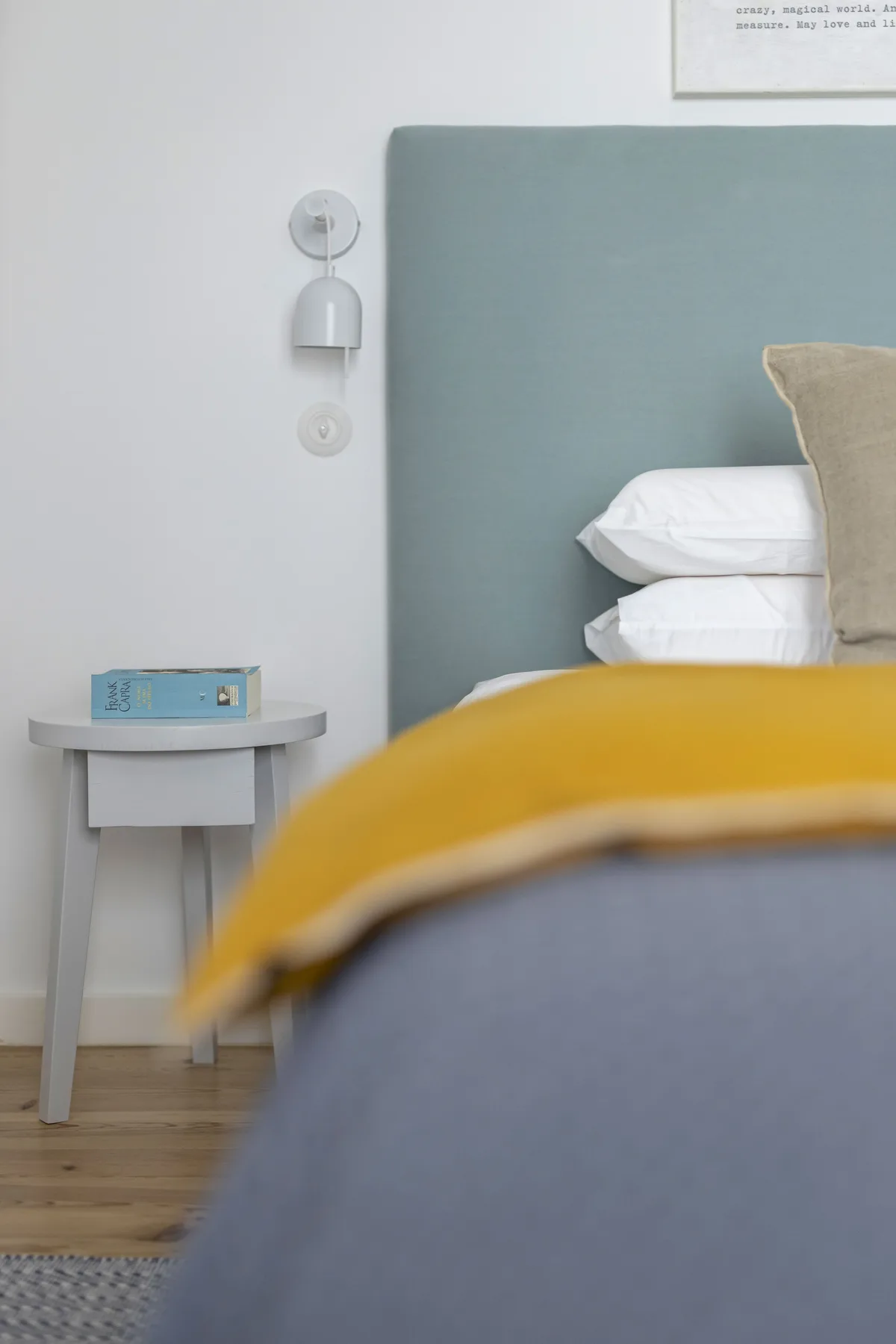 Dormitorio con cama, mesita de noche y luz de lectura en la pared.