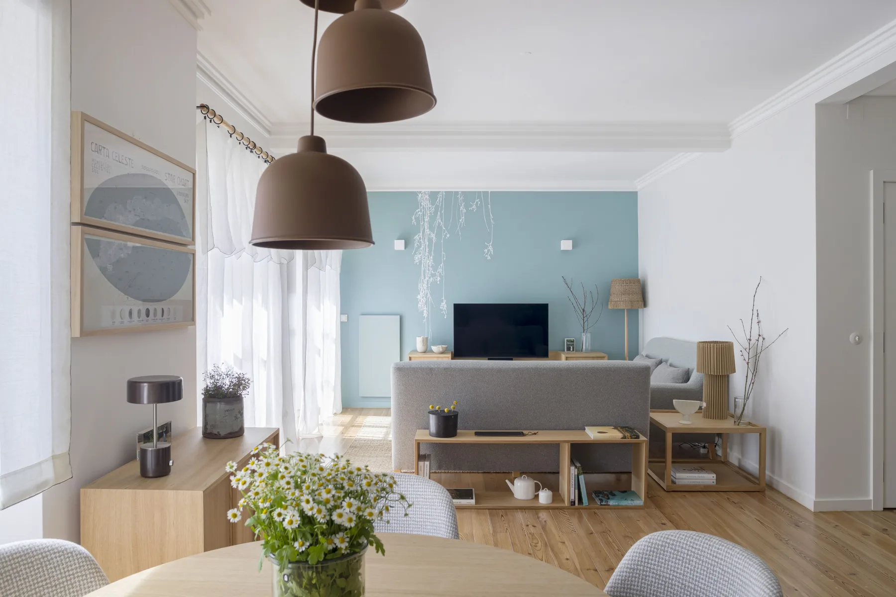 Una sala de estar con un televisor, asientos y una pared de acento azul claro.