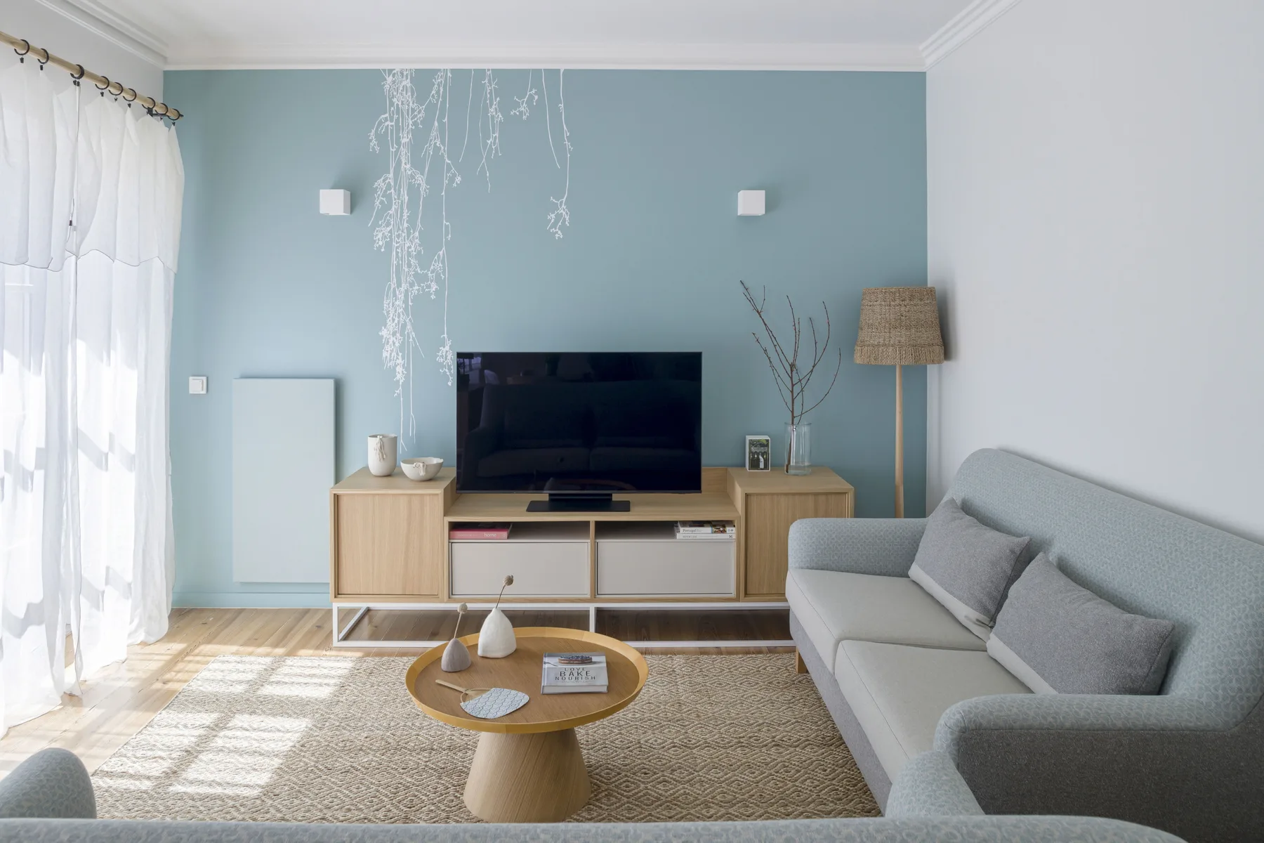 Una sala luminosa con televisor, asientos y una mesa de centro redonda.