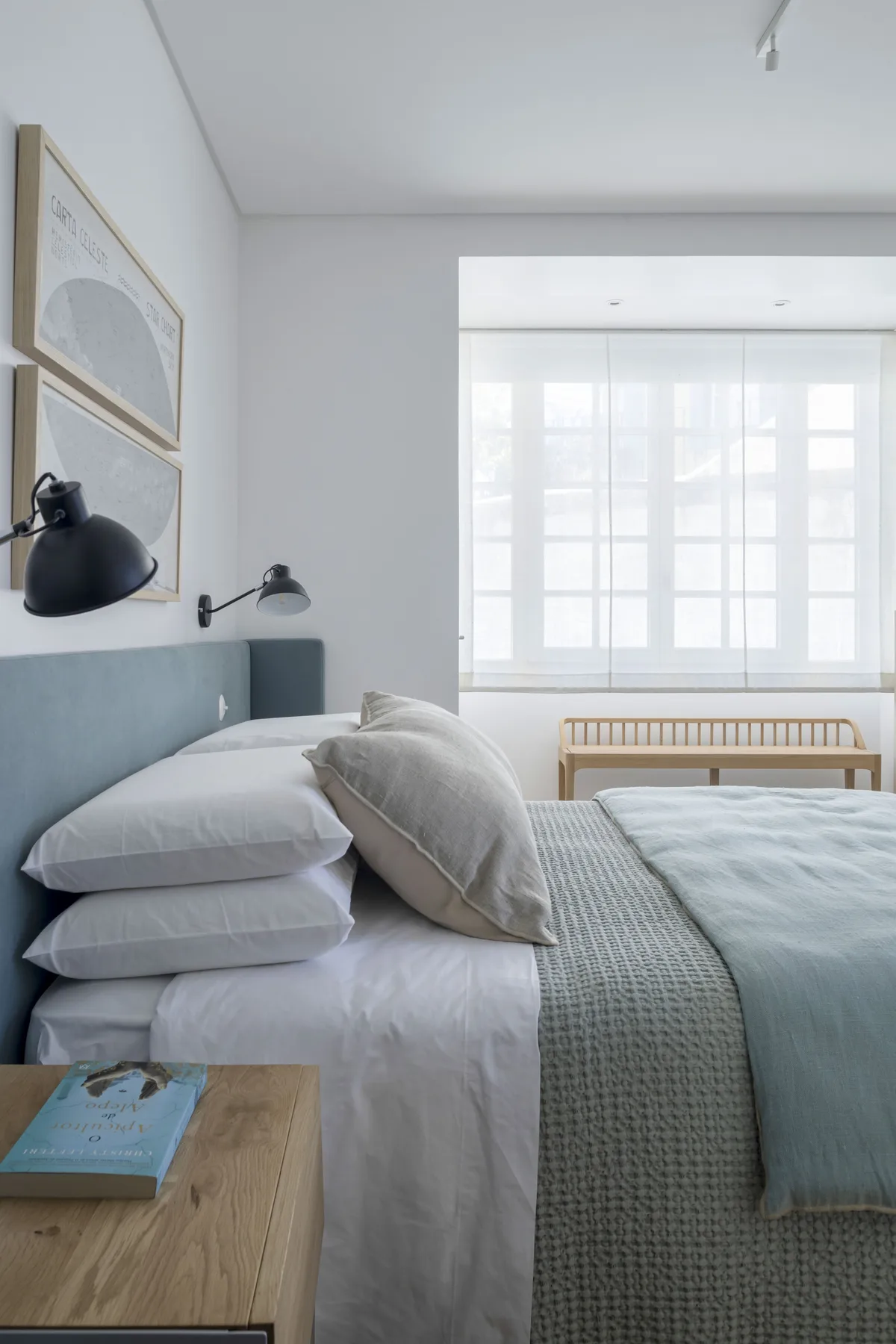 Un dormitorio luminoso con ropa de cama en capas y una ventana grande.