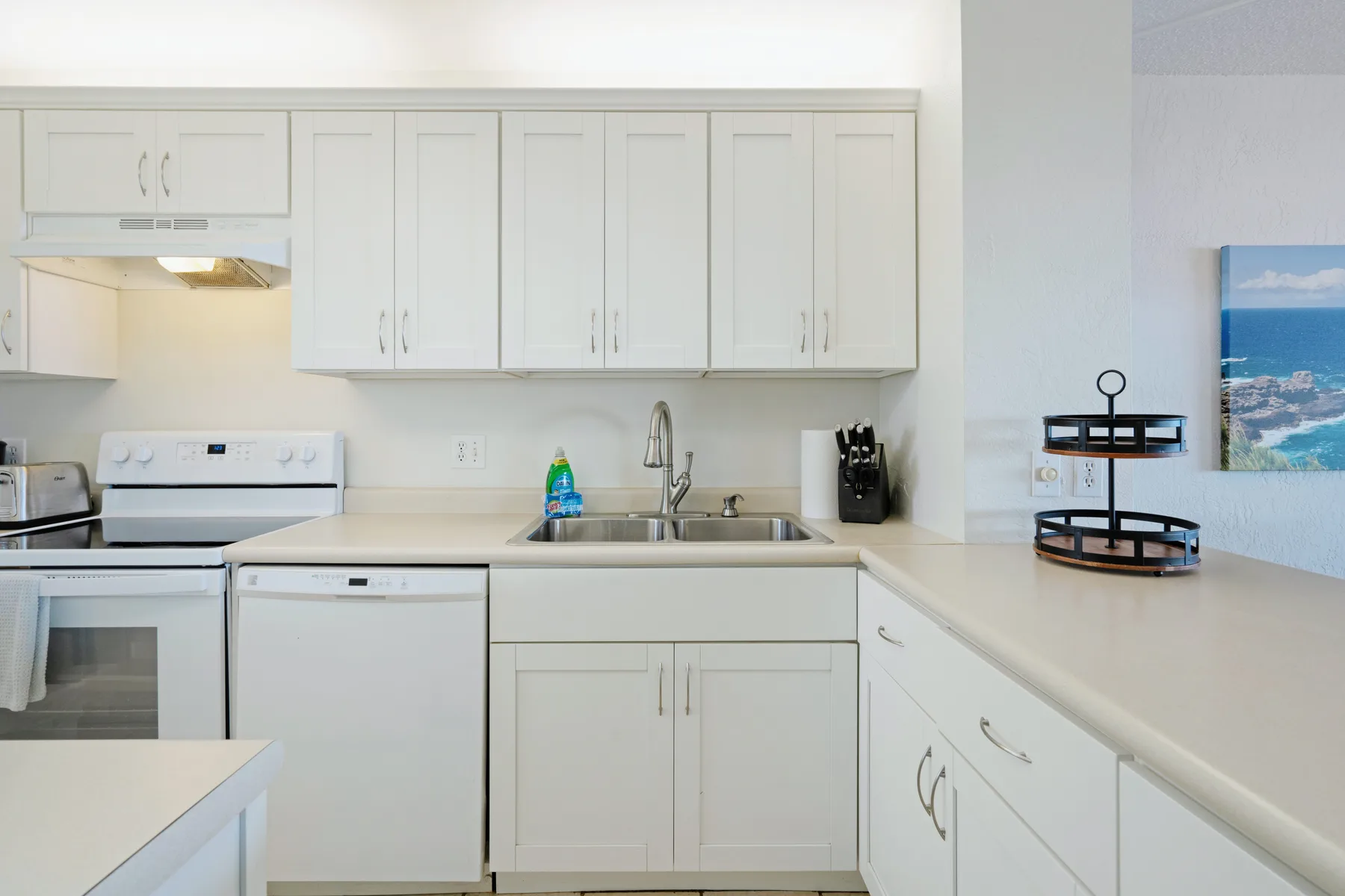Una cocina luminosa con gabinetes blancos, un fregadero y una estufa.