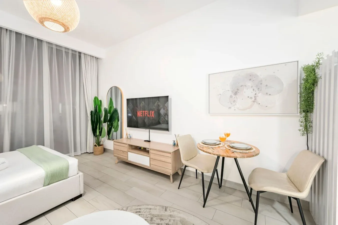 Una luminosa zona de estar con cama, mesa de comedor y televisor.