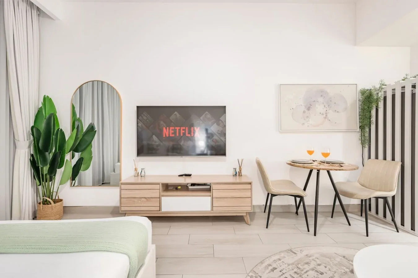 Una luminosa sala de estar con televisor, mesa de comedor y plantas frondosas.