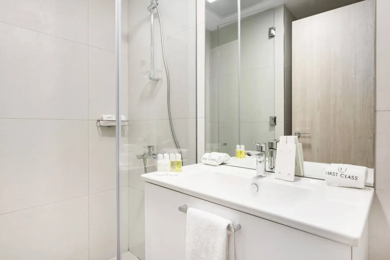 Un tocador de baño luminoso con un espejo grande y una ducha contigua.