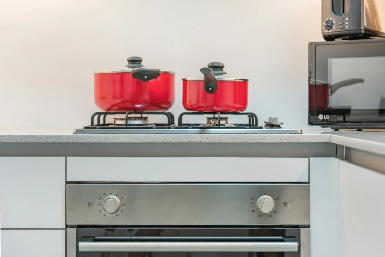 Una cocina con utensilios rojos sobre la estufa y un horno empotrado.