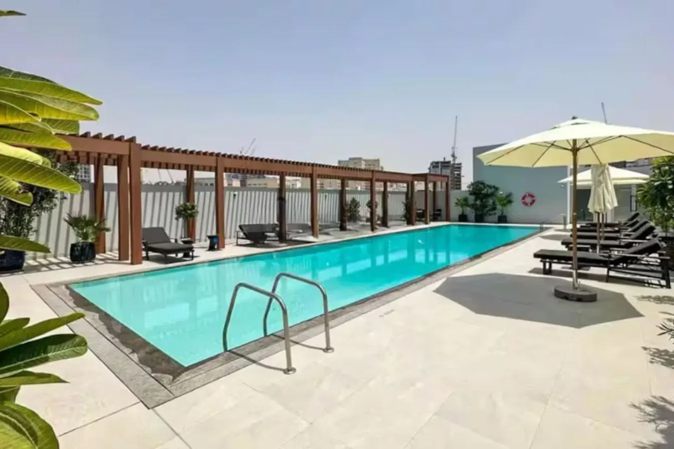 Una piscina en la azotea está rodeada de asientos reclinables y sombrillas.