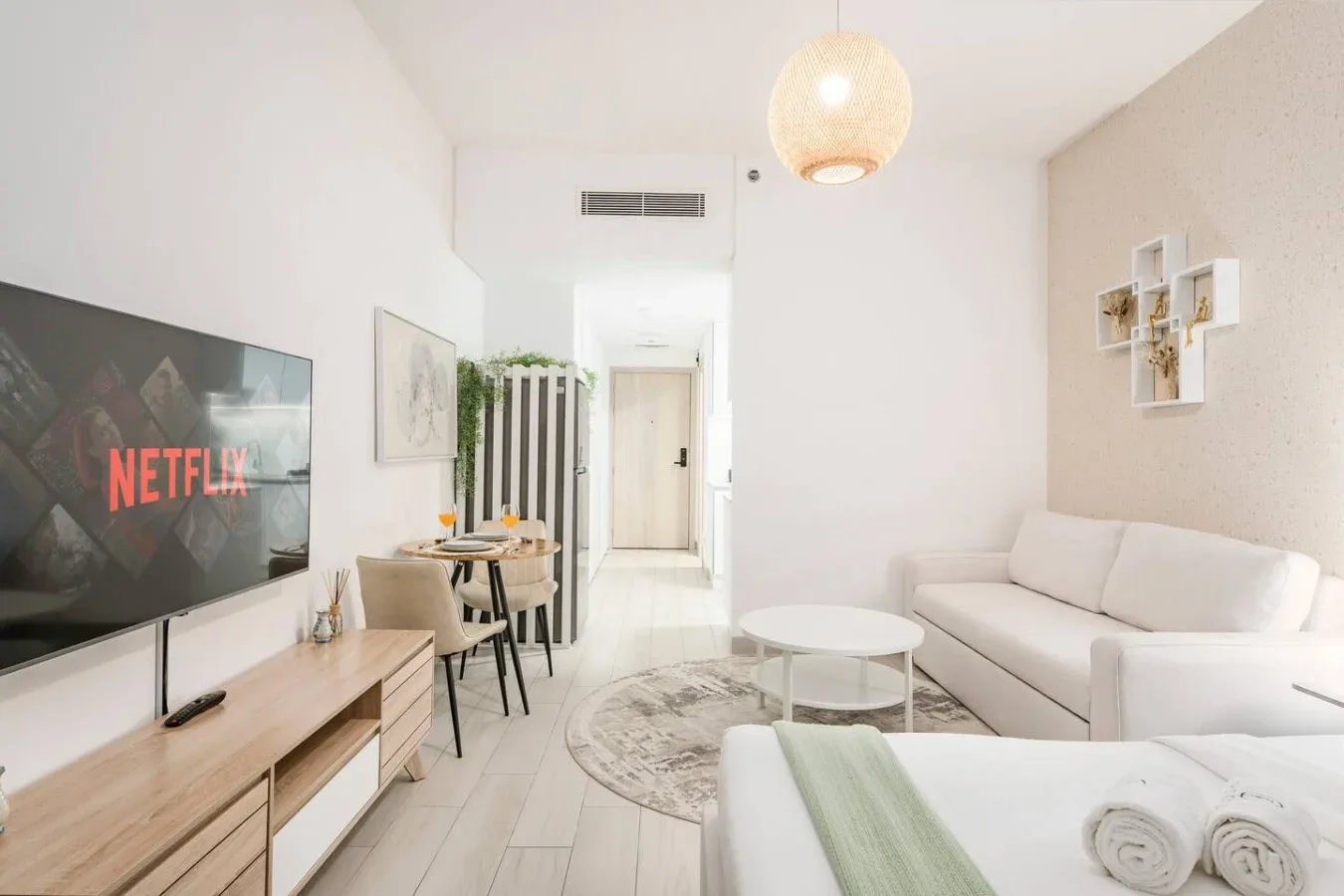 Una sala luminosa con televisor, asientos y una mesa de centro redonda.