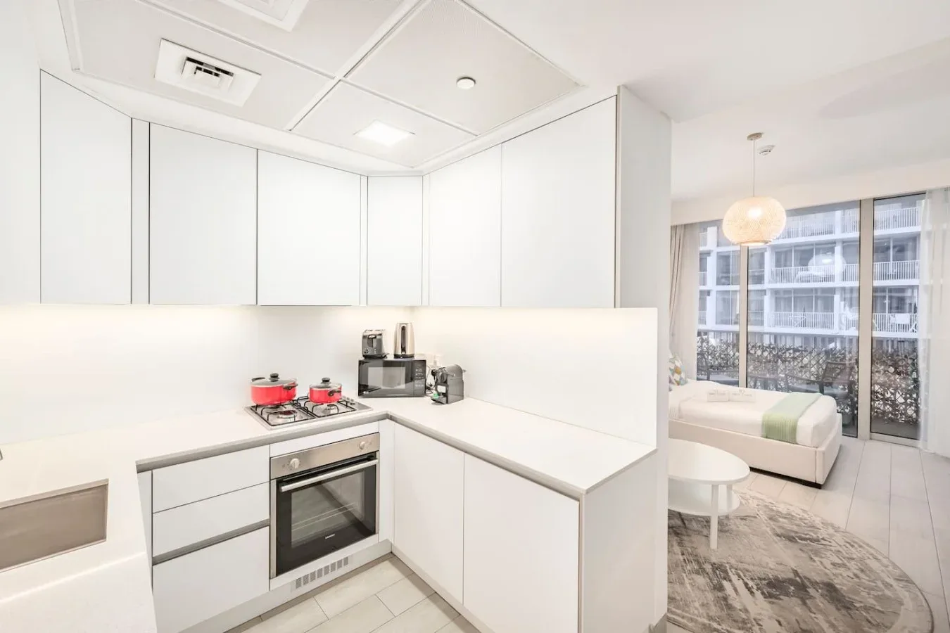 Una cocina blanca y luminosa se abre a una zona de estar junto a grandes ventanas.