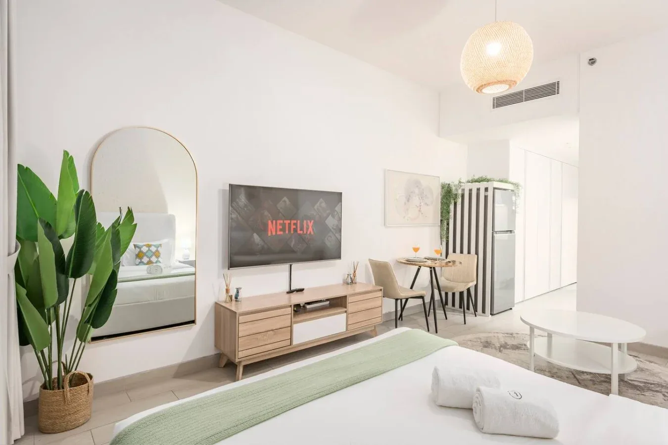 Una sala luminosa con televisor, mesa de comedor y asientos claros.