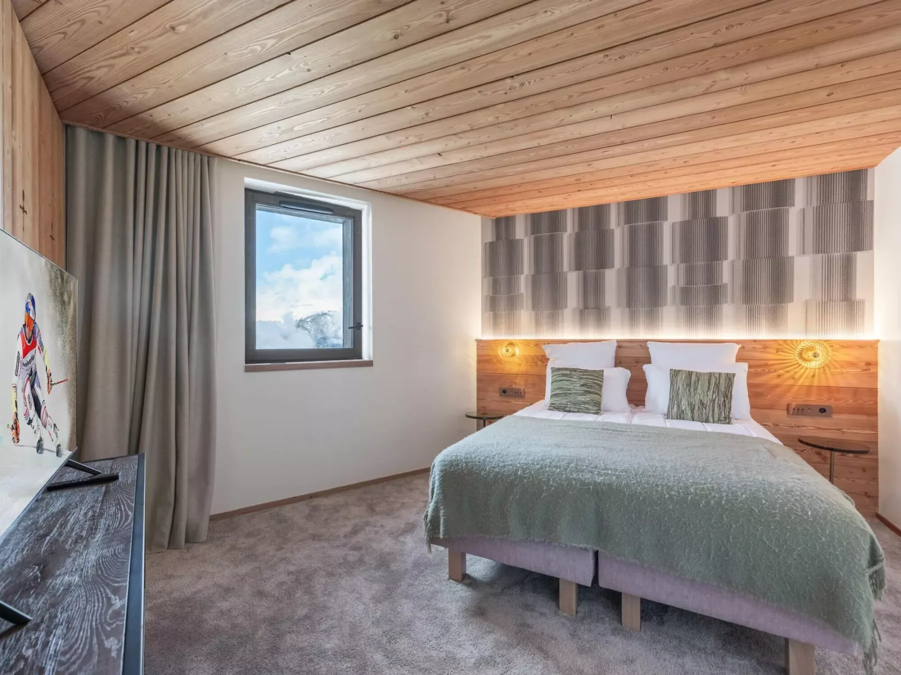 Un dormitorio con una cama bajo un techo revestido de madera y una ventana al lado.