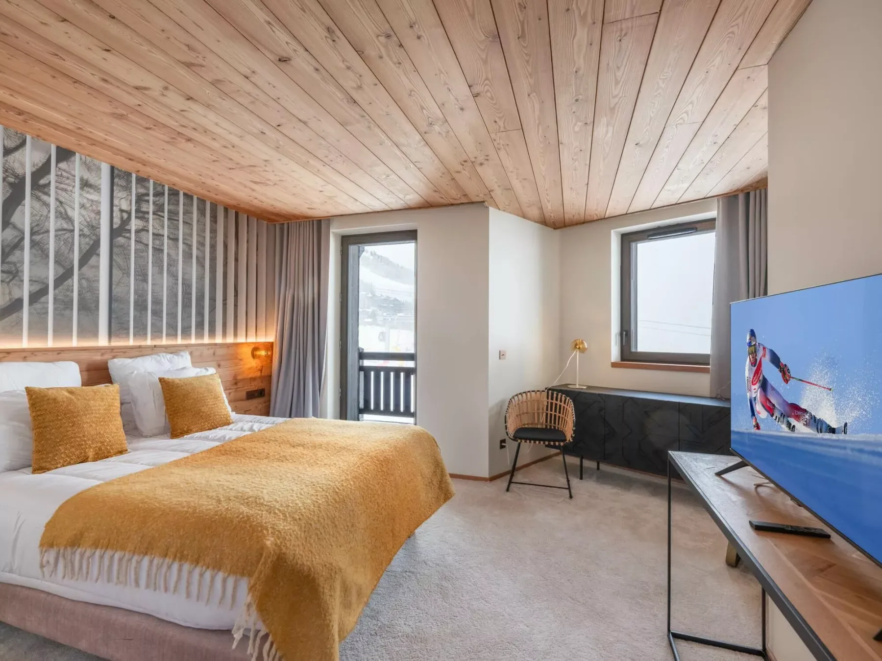 Un dormitorio con una cama, ventanas y un televisor en una esquina.