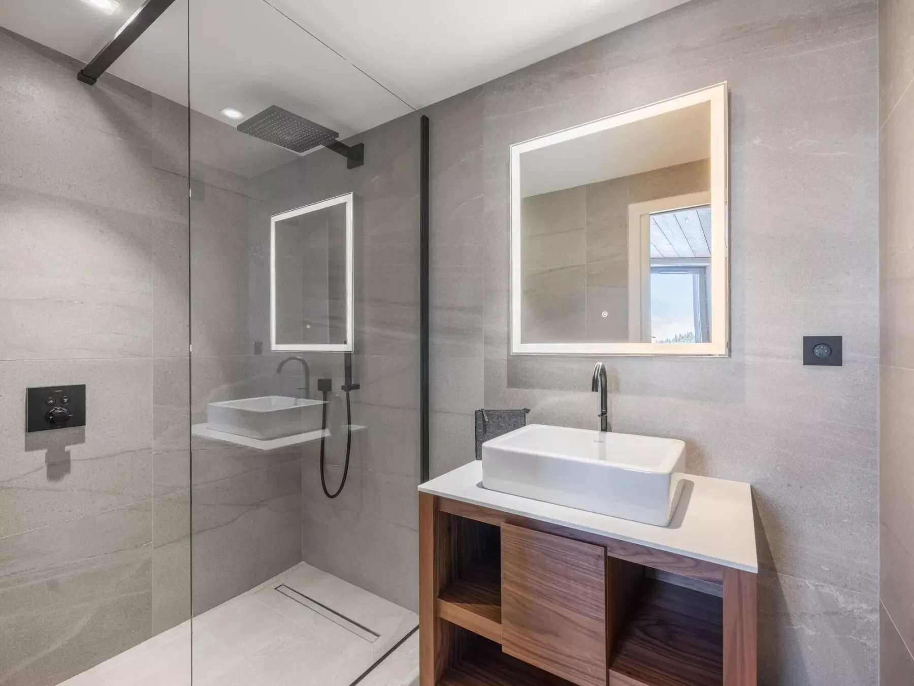 Un baño moderno con ducha a ras de suelo y lavabo sobre mueble.