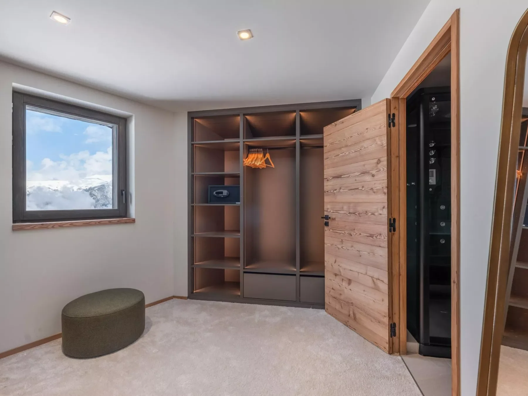 Un vestidor con armarios de madera abiertos y una ventana con vistas a montañas nevadas.