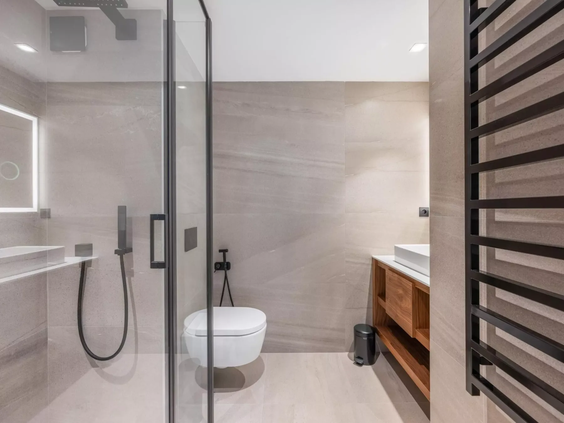 Un baño moderno con ducha de vidrio, inodoro y mueble de madera.