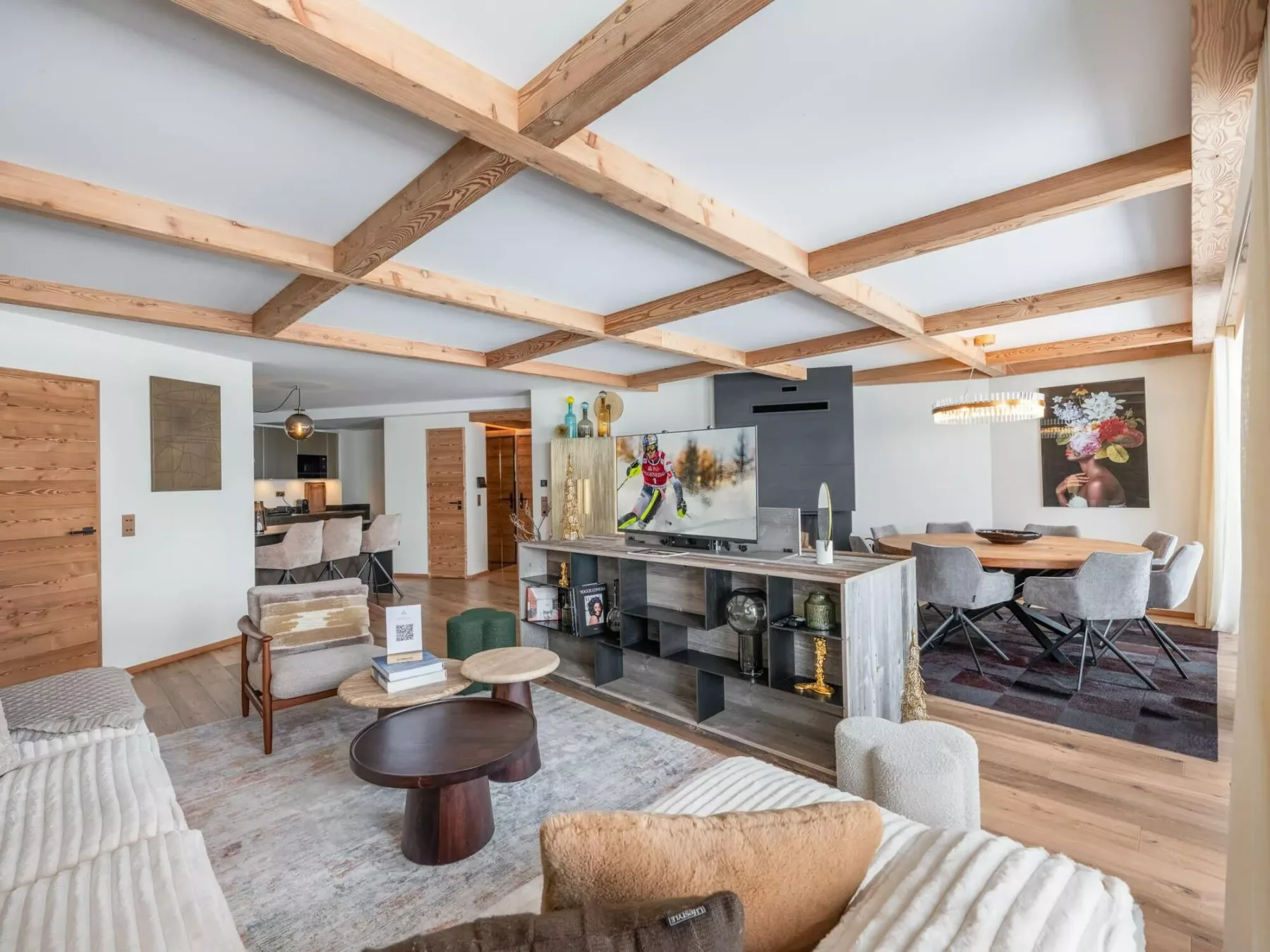 An open-plan living and dining area with exposed wooden ceiling beams and a central island.