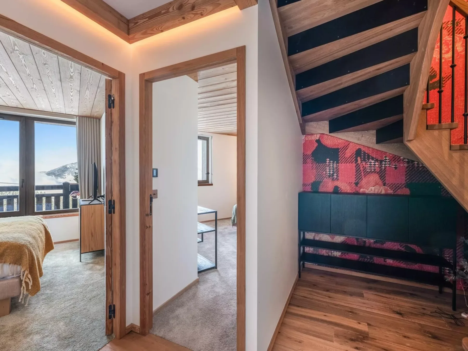 Un pasillo interior con una escalera de madera y un banco debajo.