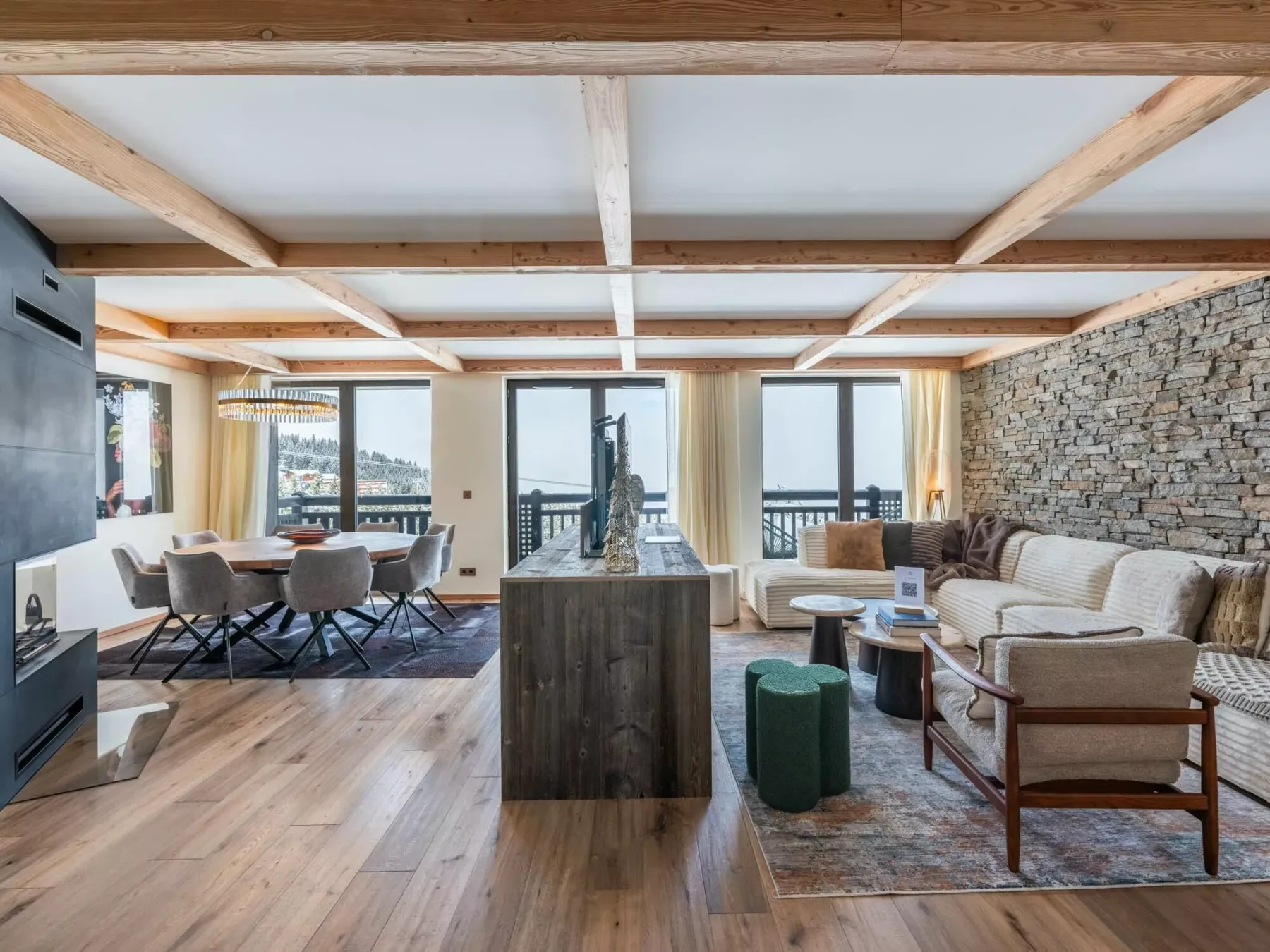 Una sala y comedor de planta abierta tienen vigas de madera expuestas y grandes ventanas.