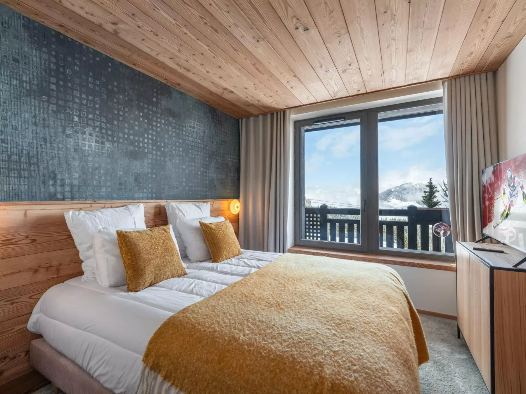 Un dormitorio con camas junto a una gran ventana con vistas a las montañas.