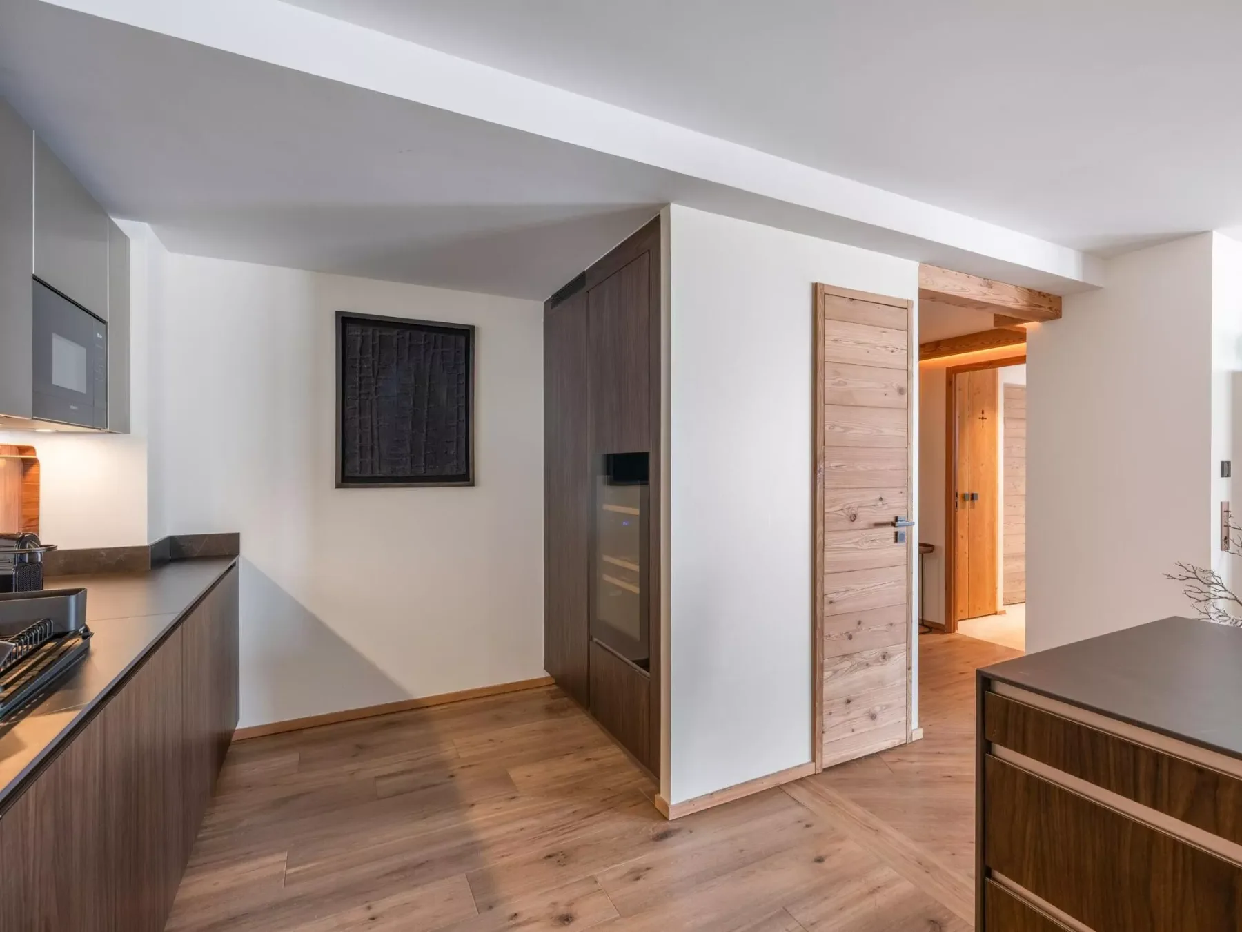 Cocina y pasillo con gabinetes de madera y un cuadro en la pared.