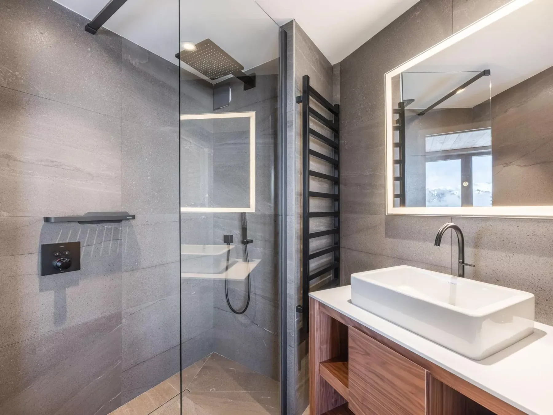 Un baño moderno con una ducha de vidrio y un lavabo blanco.