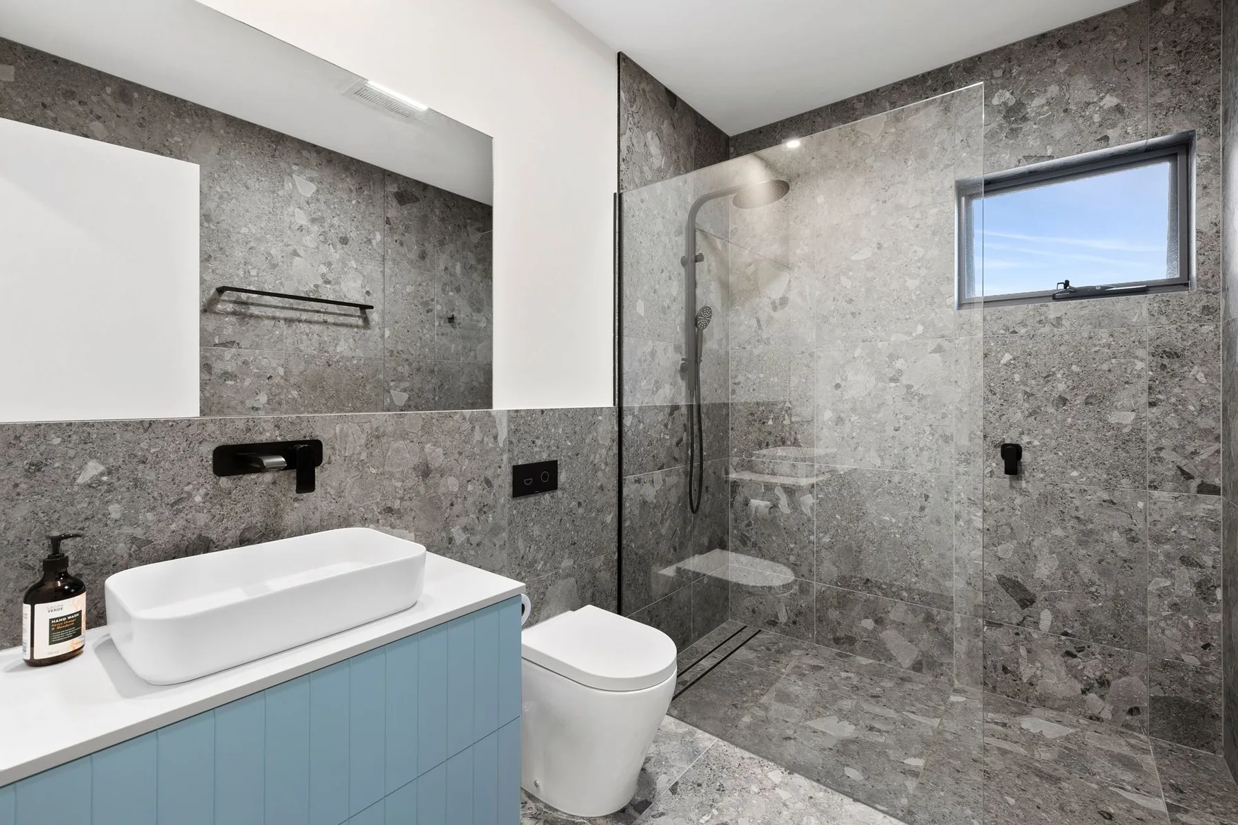 Un baño moderno con lavabo sobre encimera, inodoro y ducha de vidrio.